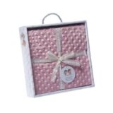 Caja de regalo con manta rosa de textura suave, decorada con un lazo y etiqueta. Ideal para bebés y ocasiones especiales.