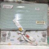 Juego de sábanas para cuna, con una manta de color azul claro y una funda con estampado de koalas y elementos naturales. Ideal para bebés, presentado en un empaque transparente.