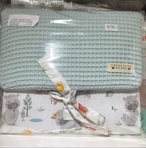 Juego de sábanas para cuna, con una manta de color azul claro y una funda con estampado de koalas y elementos naturales. Ideal para bebés, presentado en un empaque transparente.